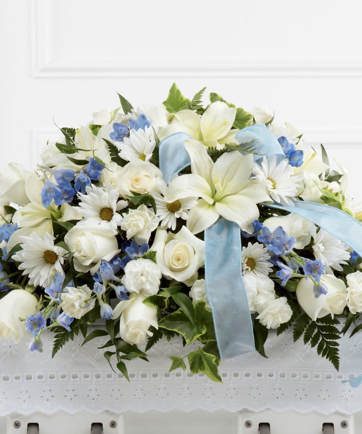 White floral arrangement with blue ribbon and blue accents