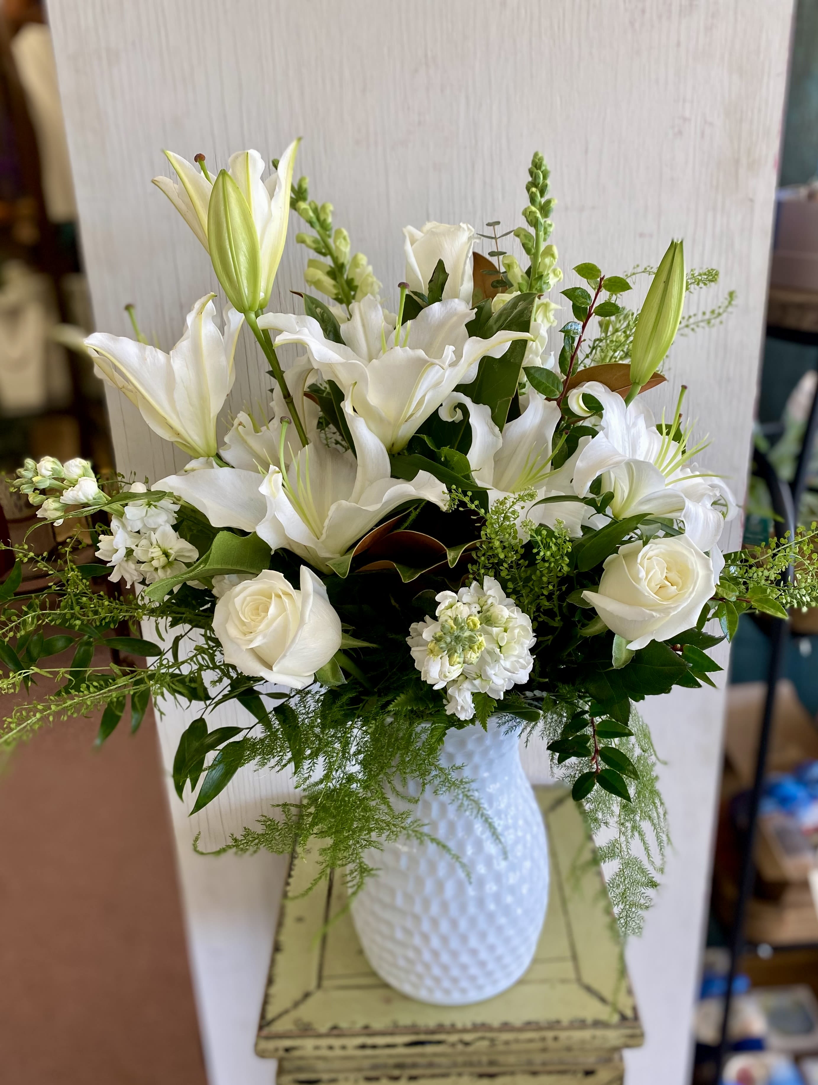 White lilies and roses arranged in a white vase