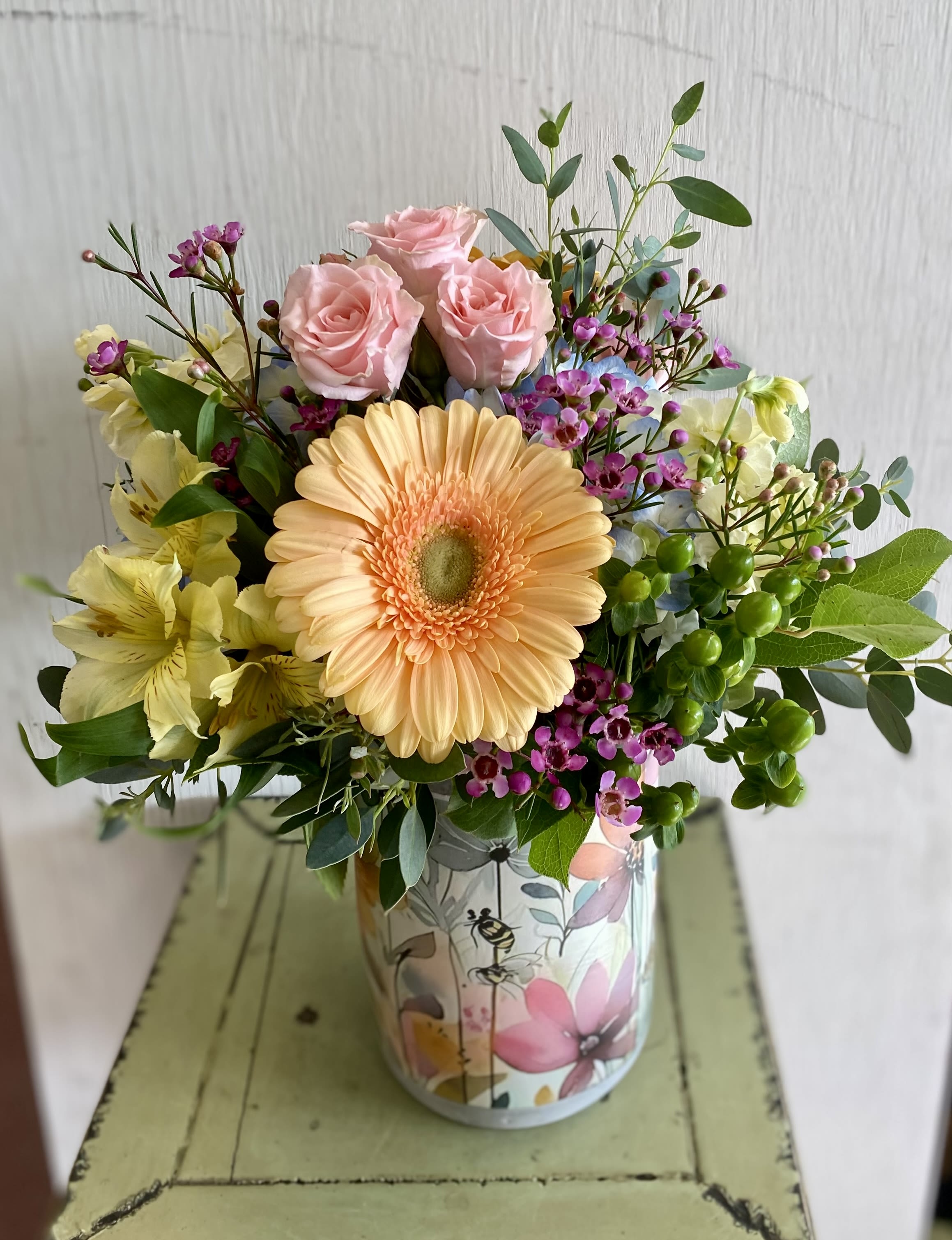 Mixed bouquet with pink roses and a peach gerbera daisy in a floral tin
