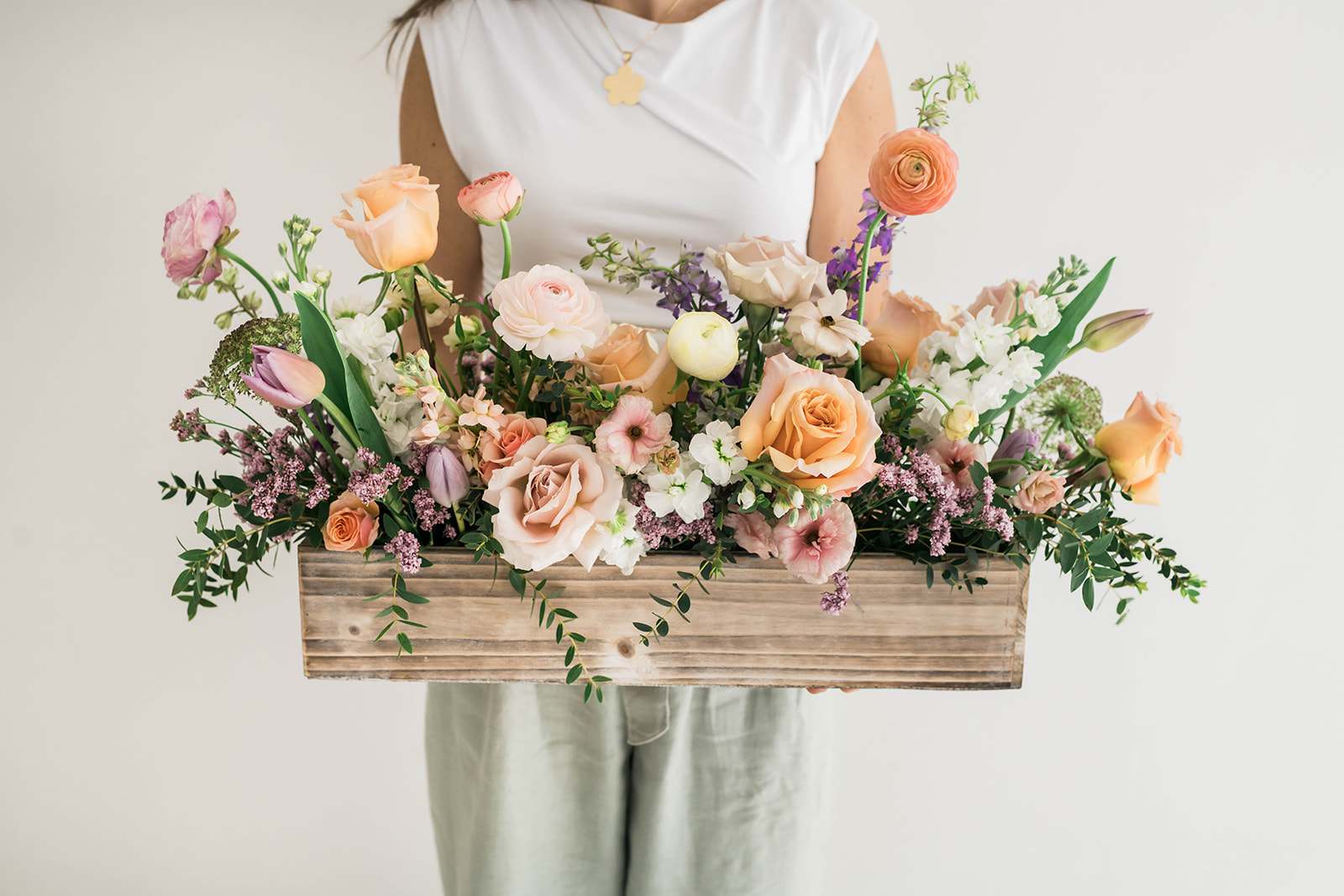 Mixed pastel flowers arranged in a wooden box