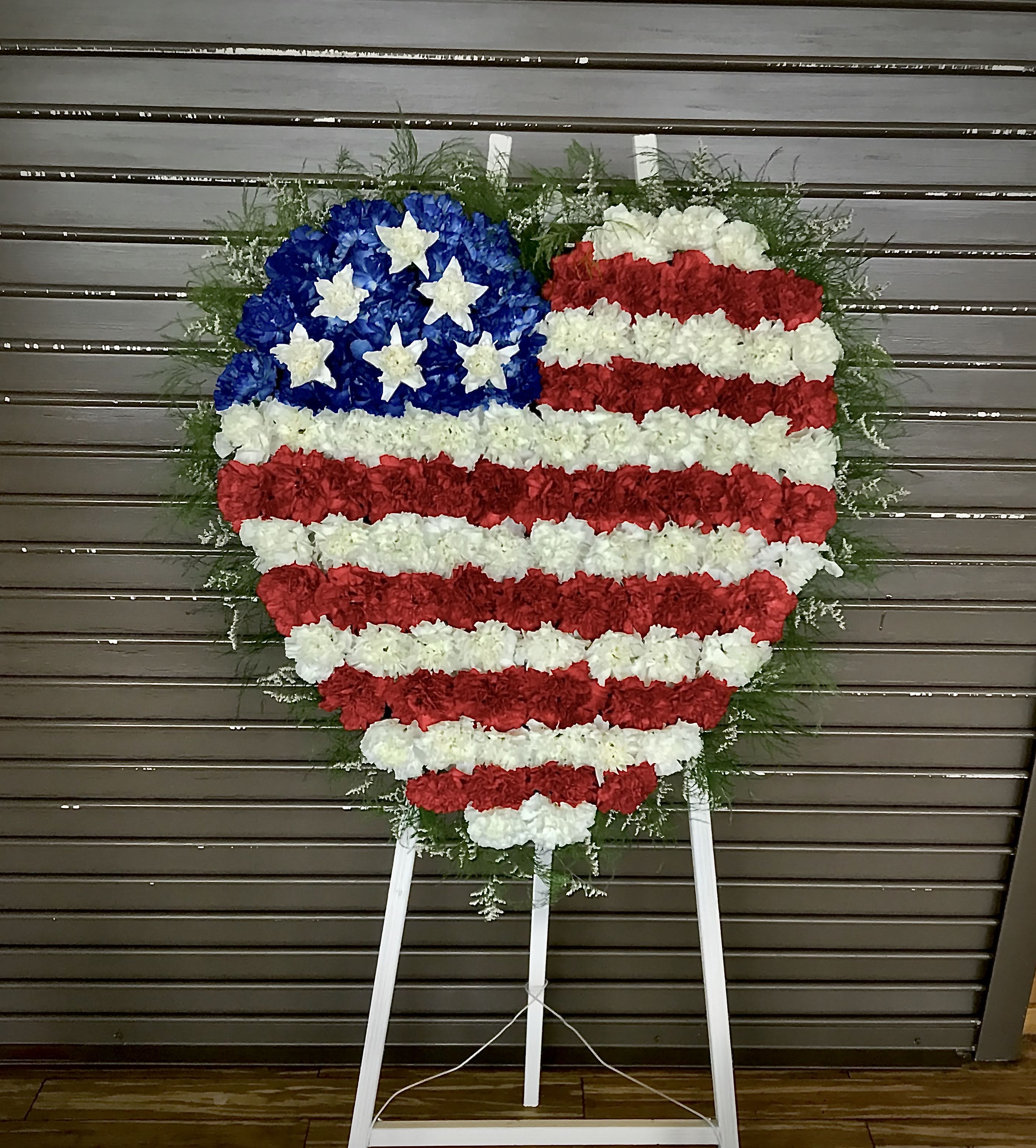 Heart-shaped standing floral wreath in red, white, and blue styled like the American flag
