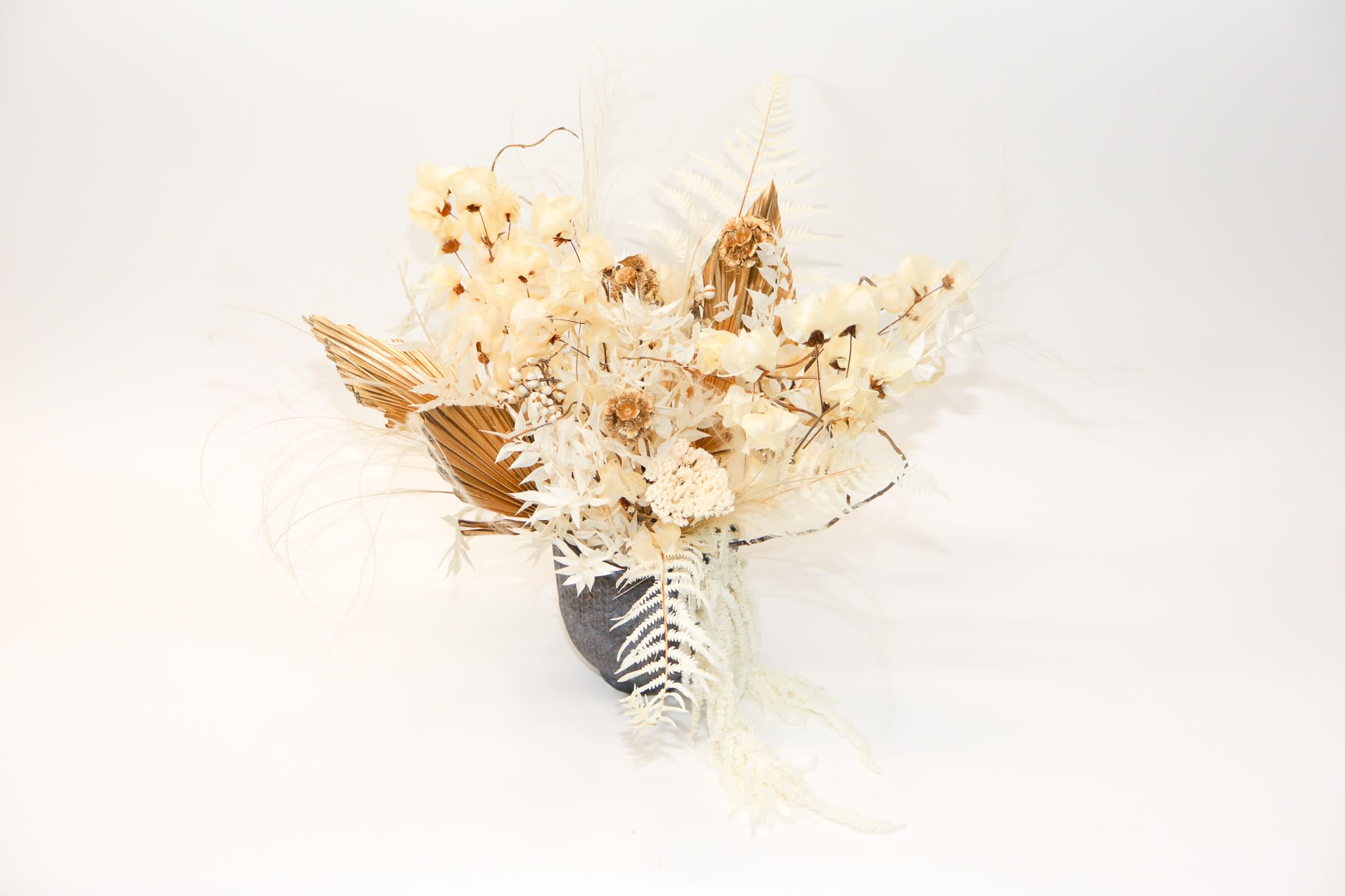 Cream dried floral arrangement in a dark vase
