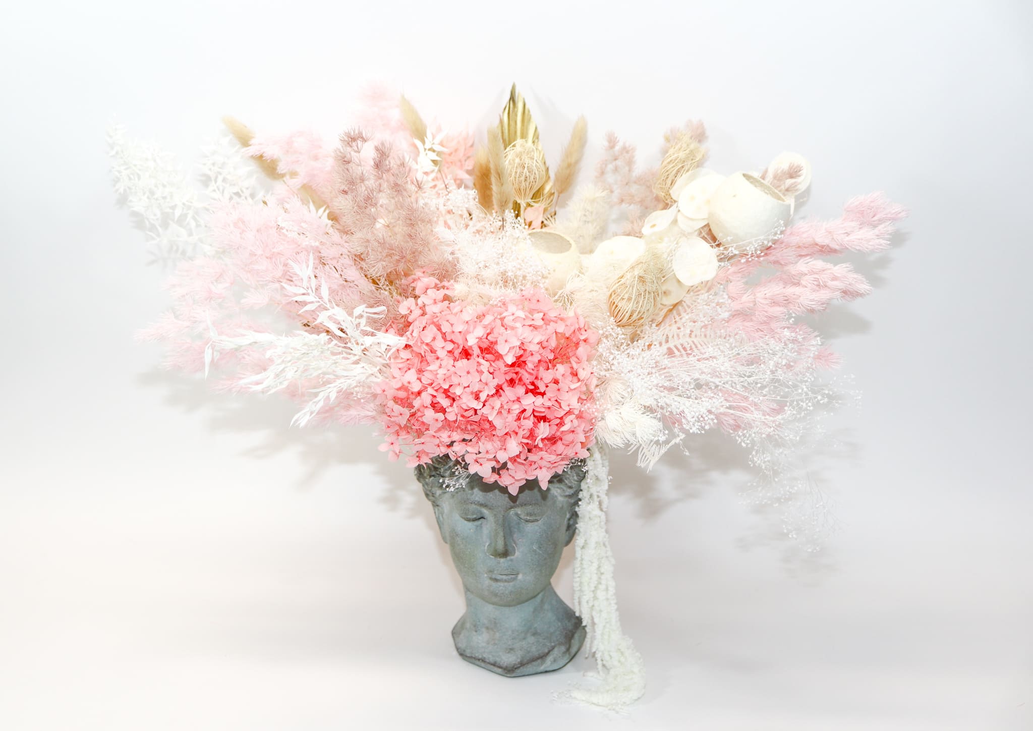 Pink and white dried floral arrangement in a sculpted face vase