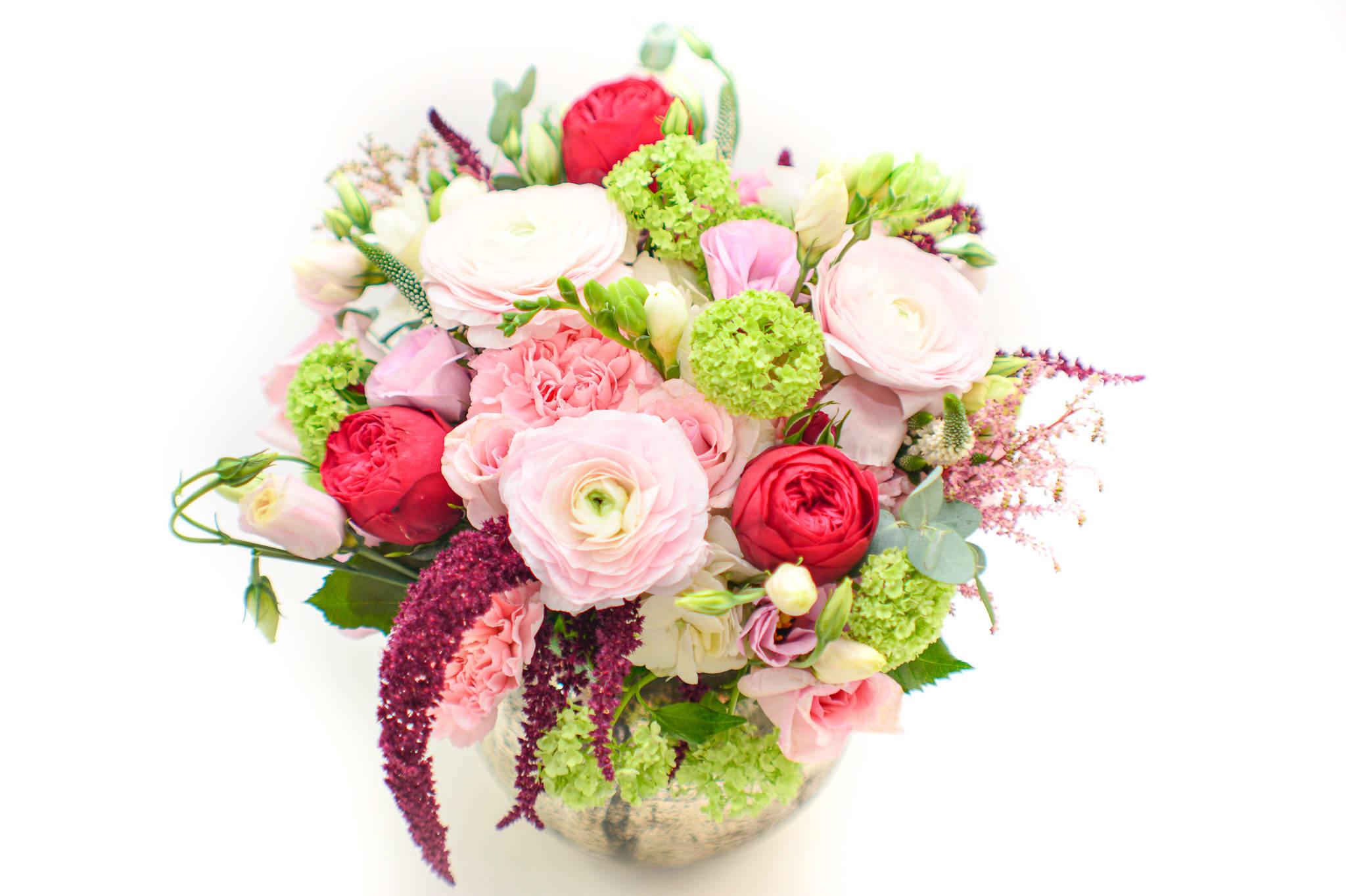 Mixed pink and red flowers arranged in a round vase