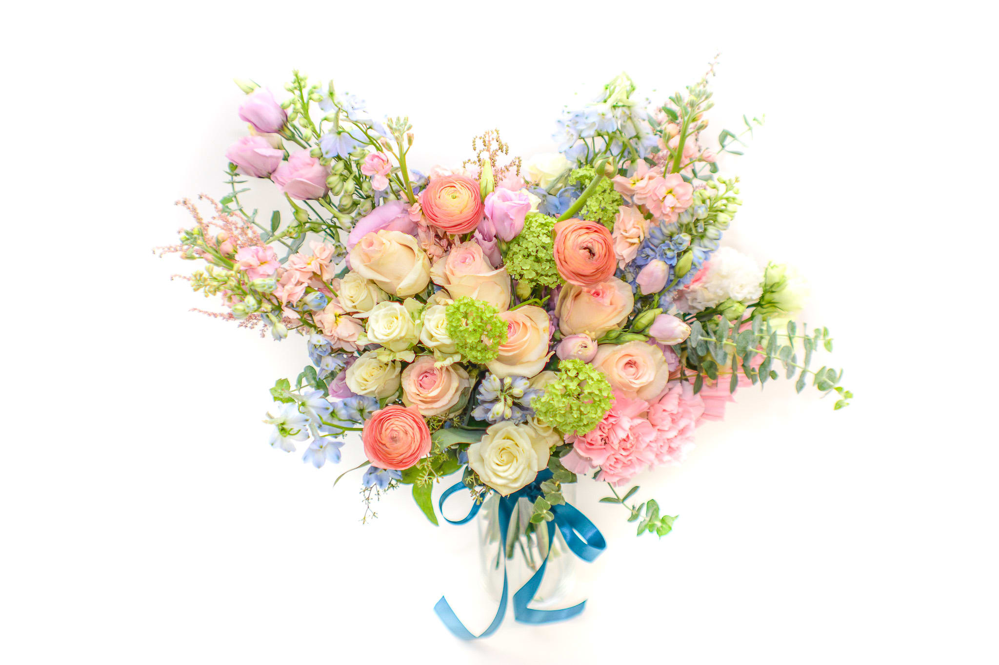 Pastel mixed flower bouquet with a blue ribbon in a clear vase