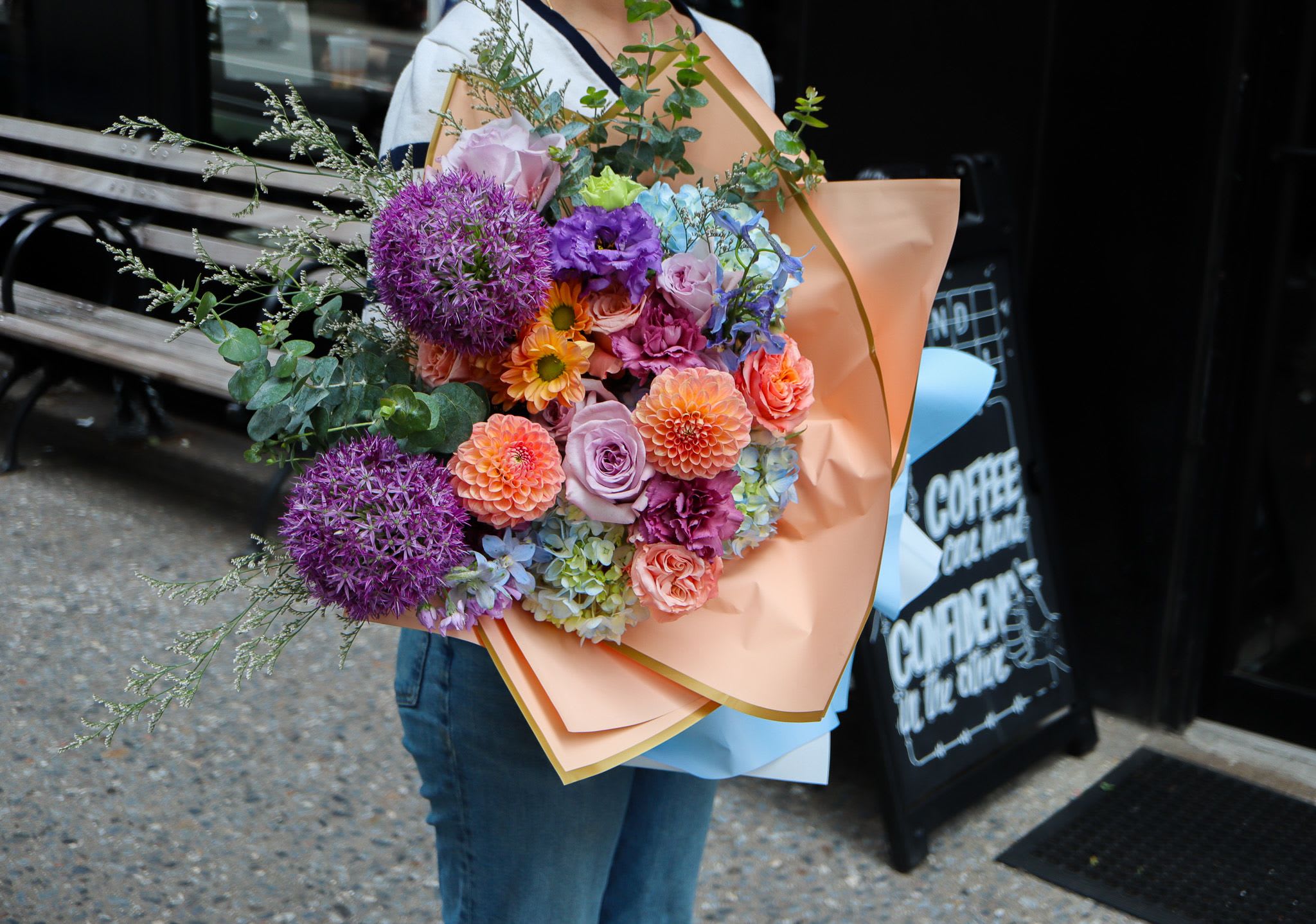 Summer Haze - Vibrant Hand-Tied Bouquet (No Vase Included) Bring color and joy into any space with this stunning hand-tied bouquet, thoughtfully arranged with an artful mix of seasonal blooms. This lush arrangement features bold purple alliums, cheerful dahlias, romantic roses, and soft hydrangeas, accented with delicate greenery and wrapped in premium paper for a sophisticated finish.