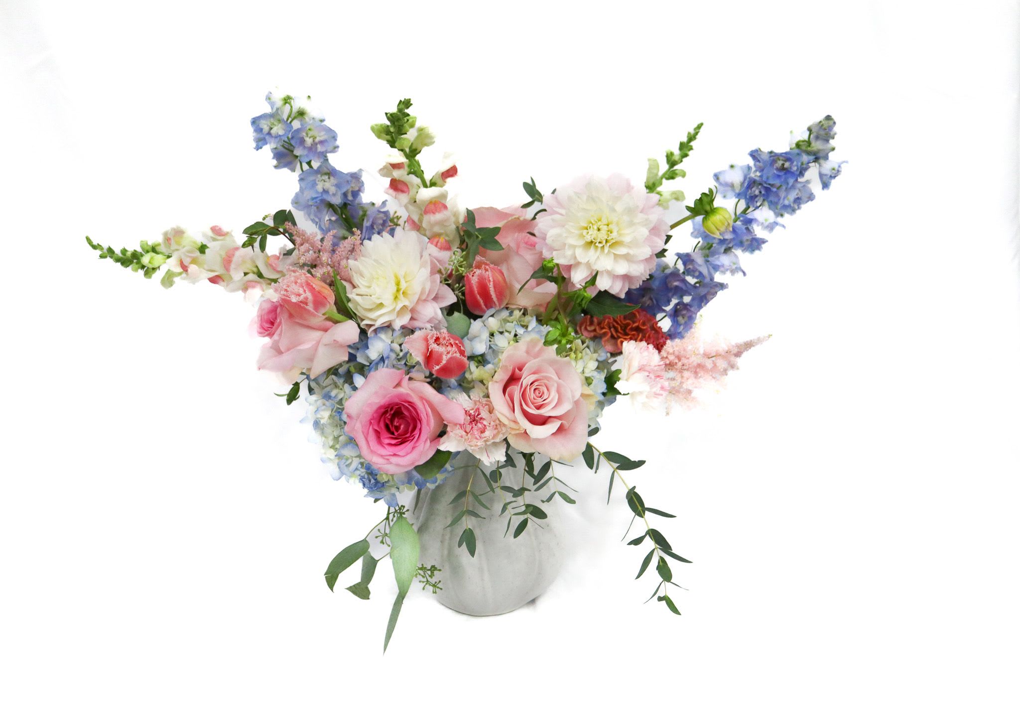 Pink and blue mixed flower arrangement in a white vase