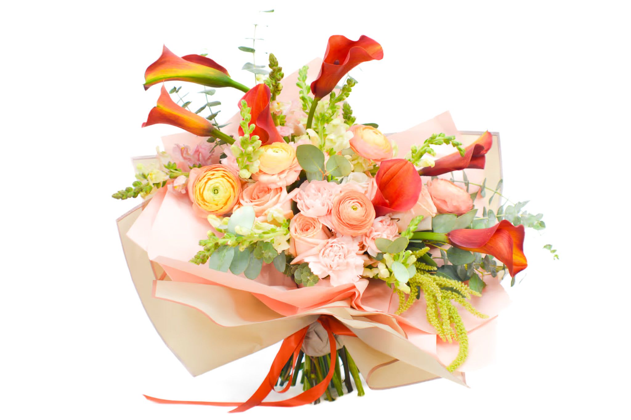 Bouquet of orange calla lilies and peach roses wrapped in pink paper