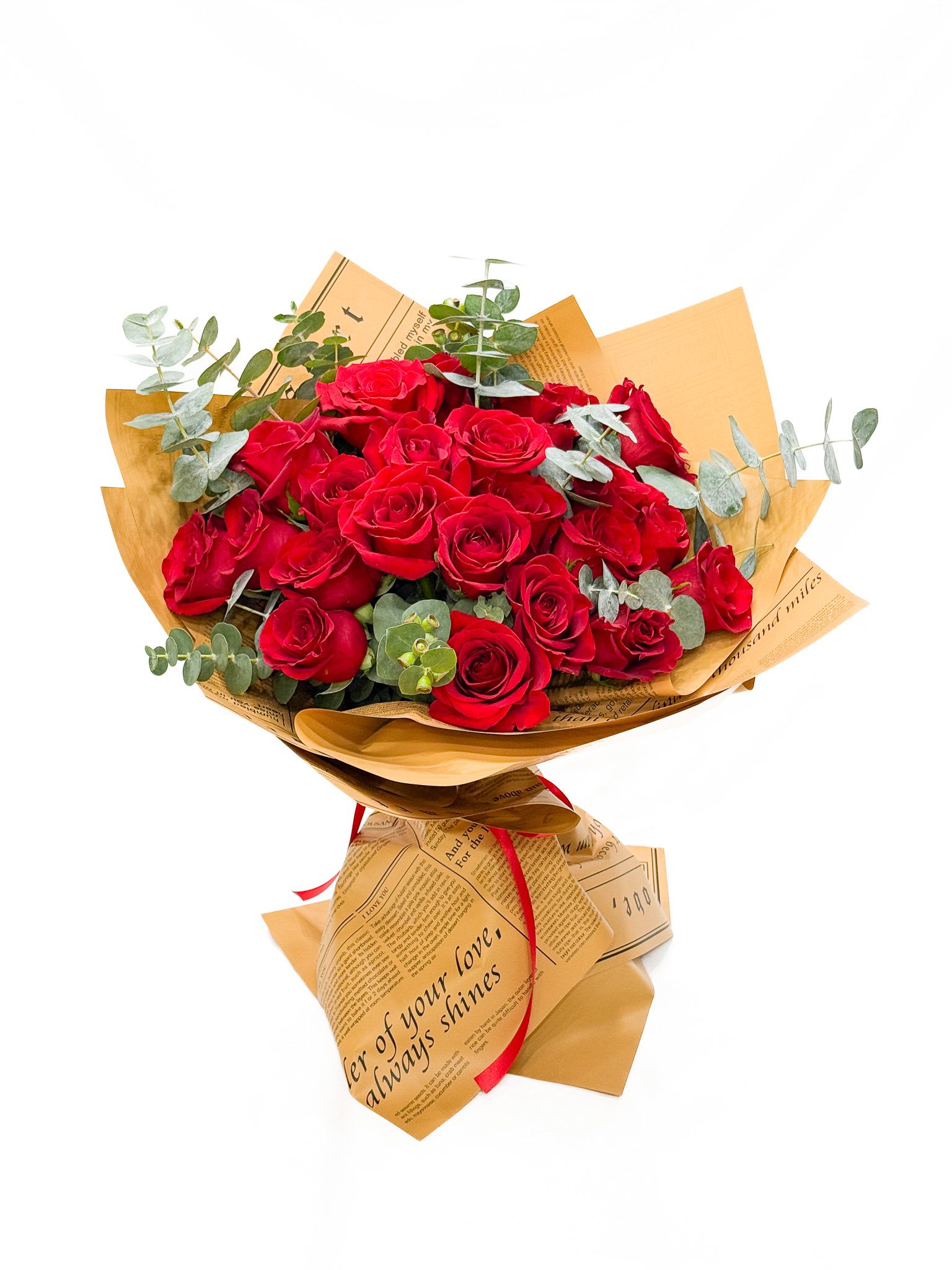 Bouquet of red roses wrapped in tan paper with eucalyptus