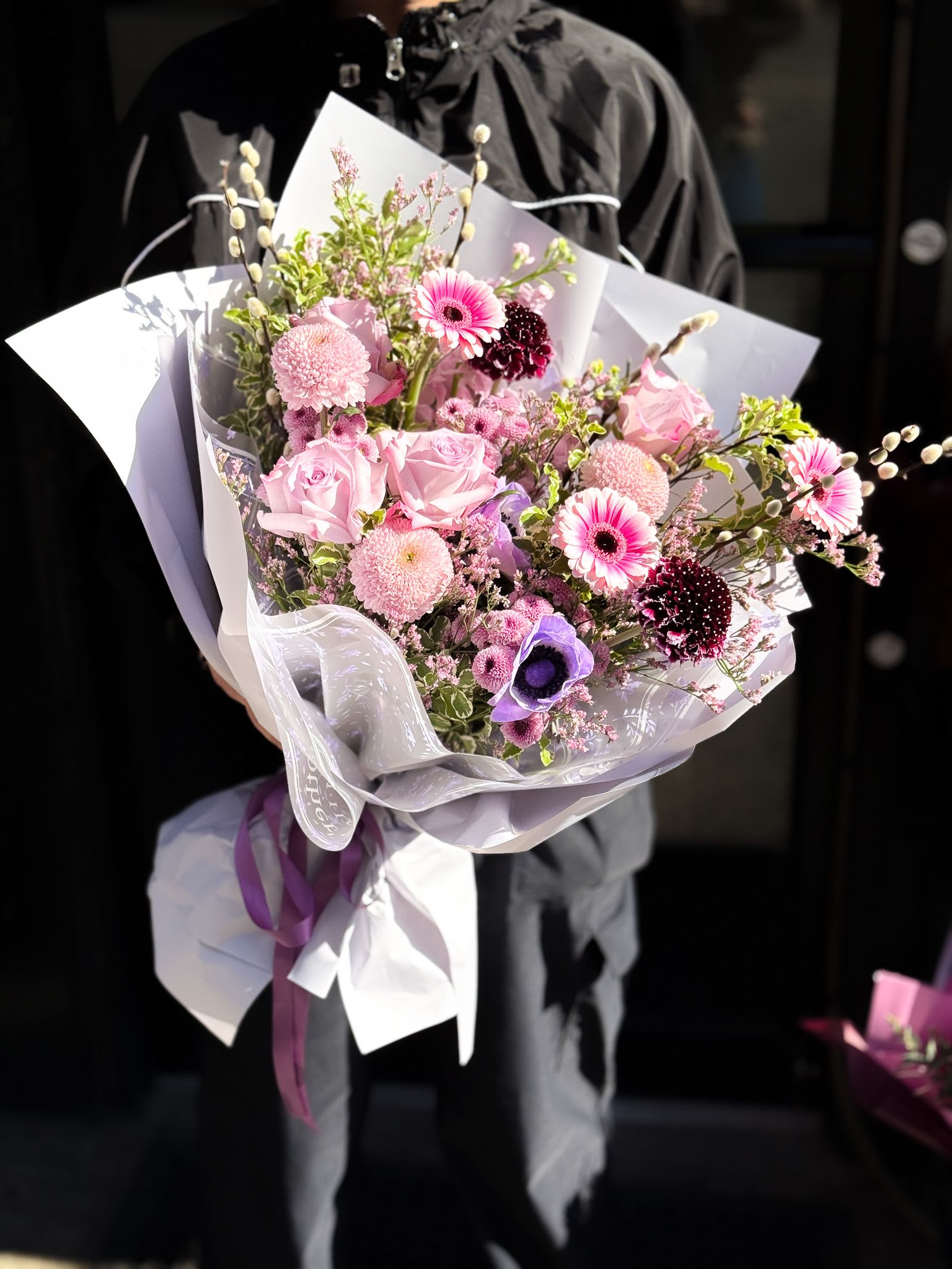 Pink and purple mixed bouquet wrapped in white paper with ribbon