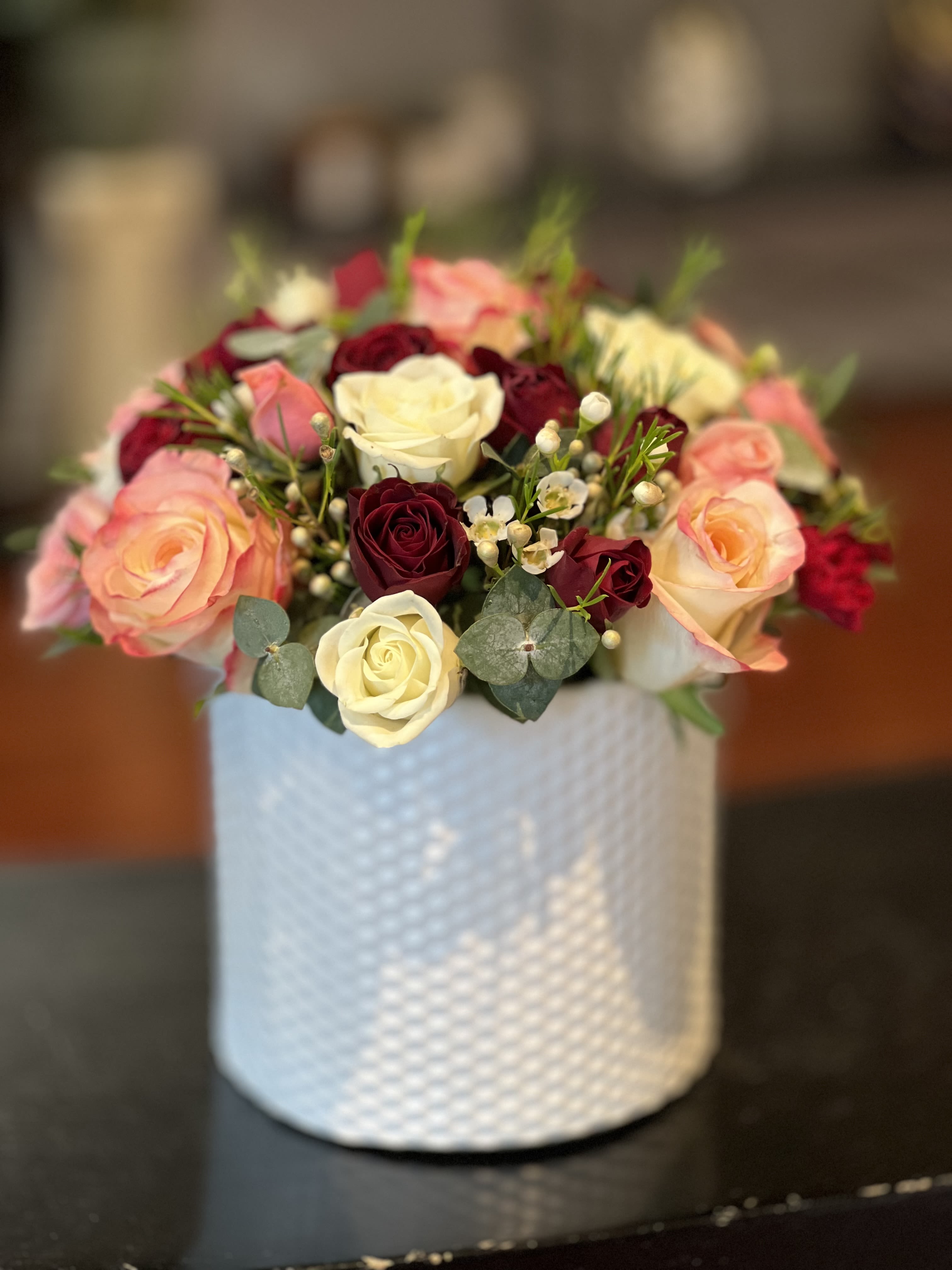 Bouquet of pink, cream, and burgundy roses in a white textured vase
