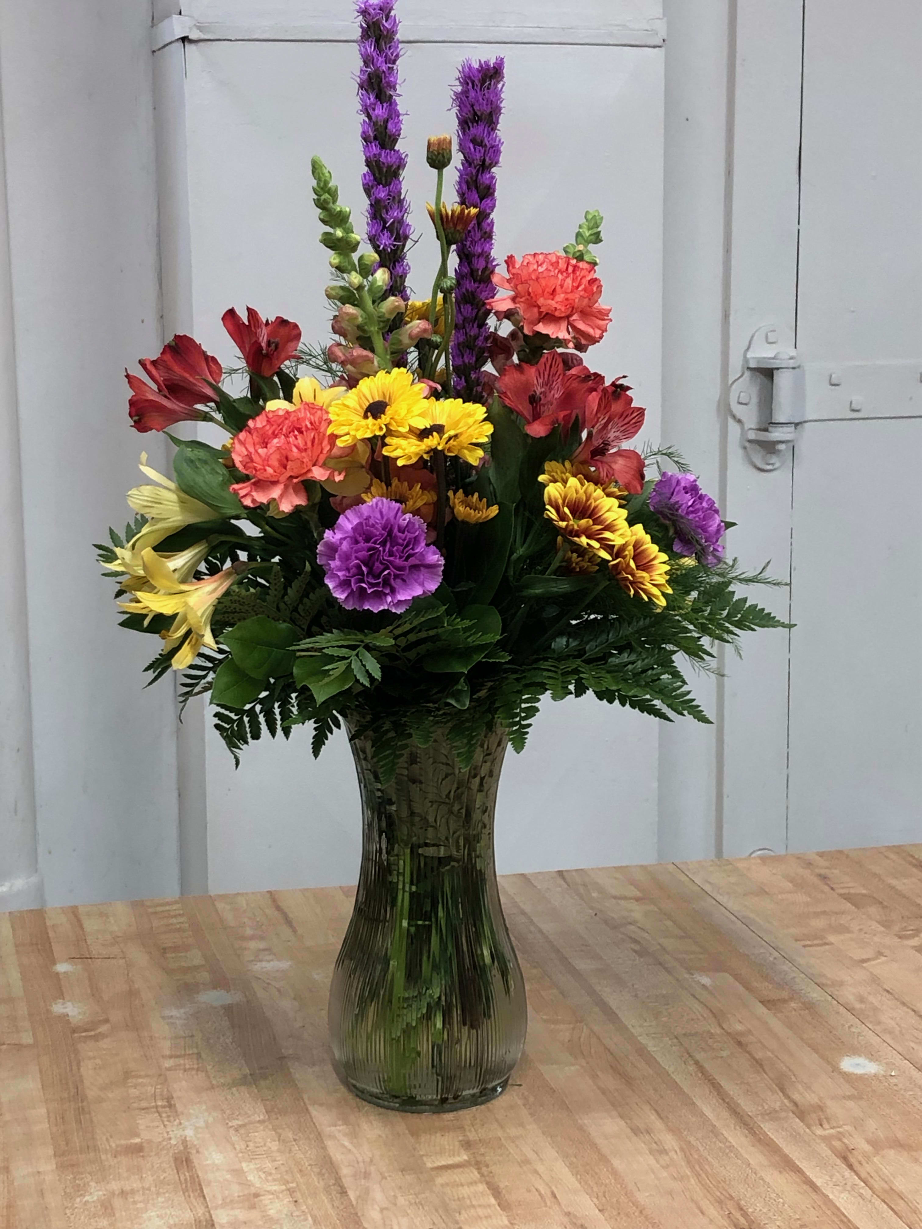 Colorful mixed flower arrangement in a tall glass vase