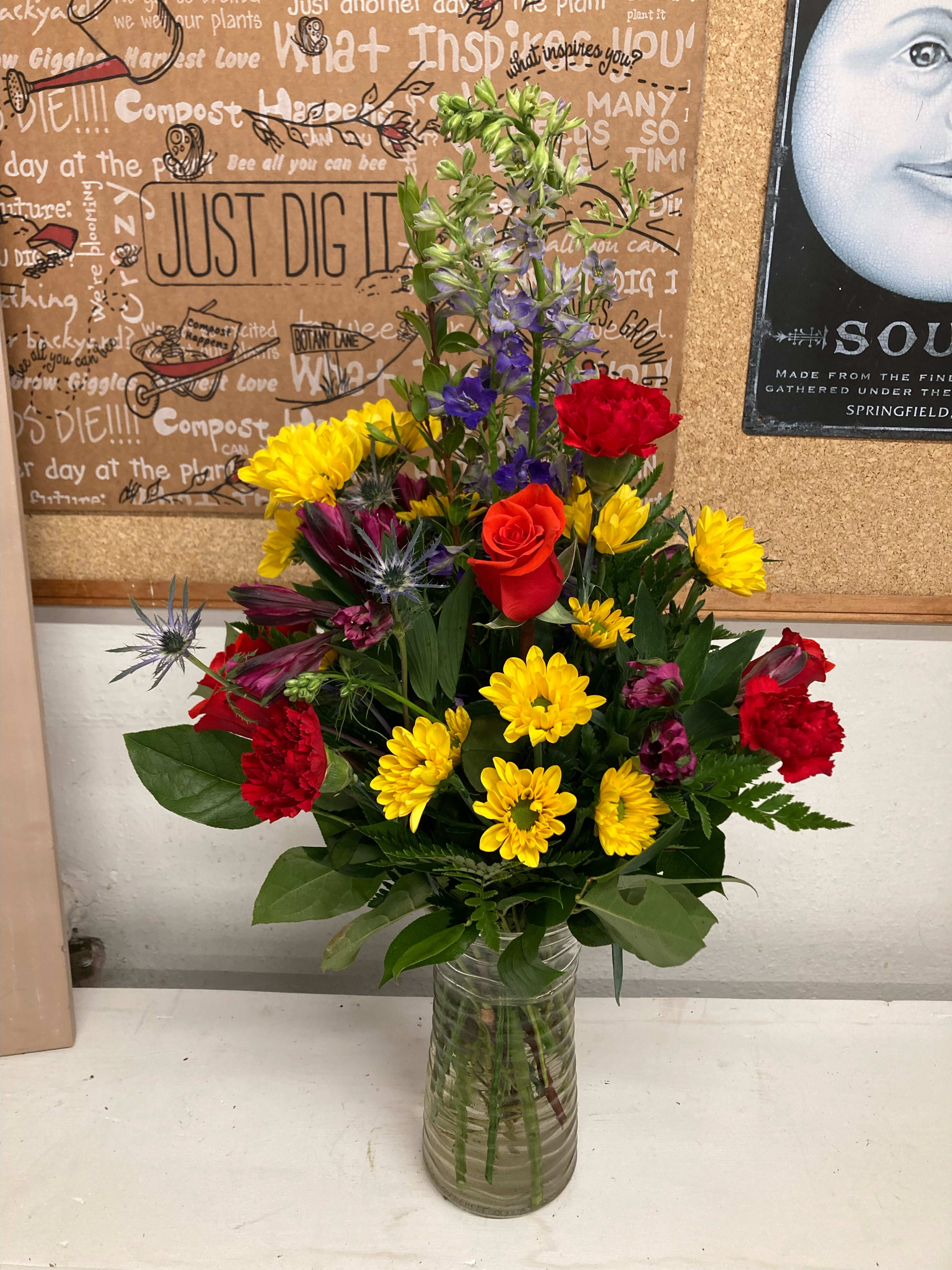 Mixed bouquet in a clear glass vase with yellow, red, and purple flowers