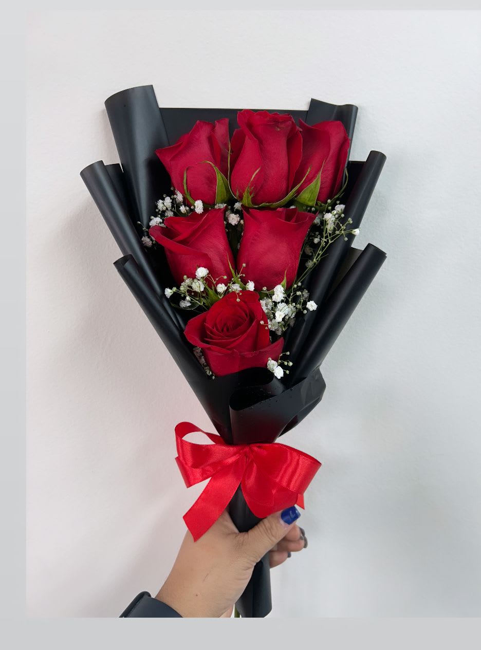 Bouquet of red roses wrapped in black paper with a red ribbon