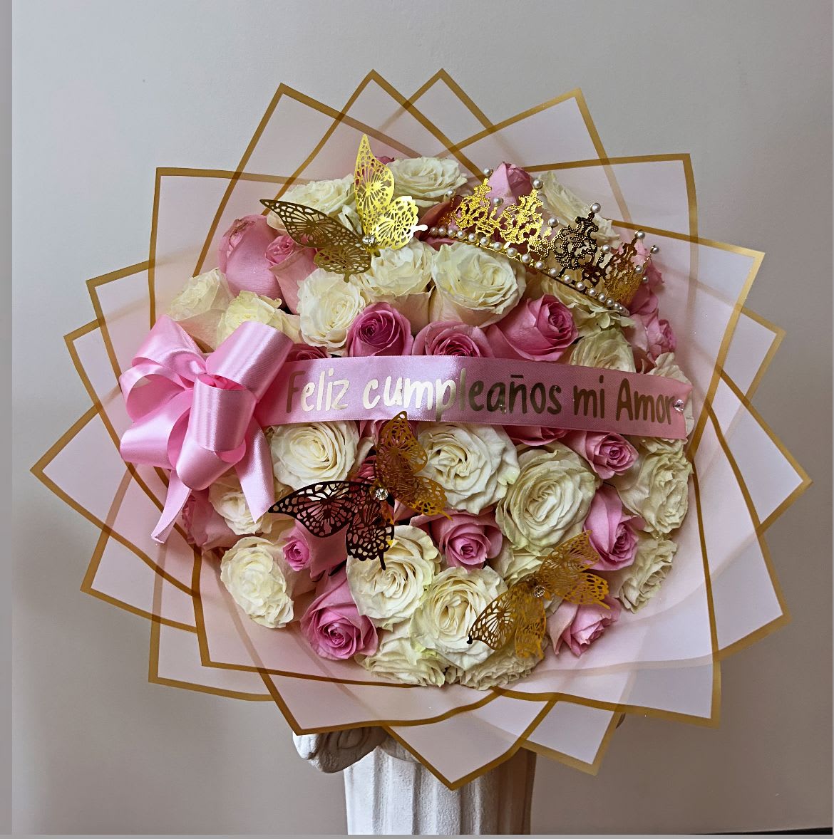 Large bouquet of pink and white roses with a pink ribbon and butterfly decorations