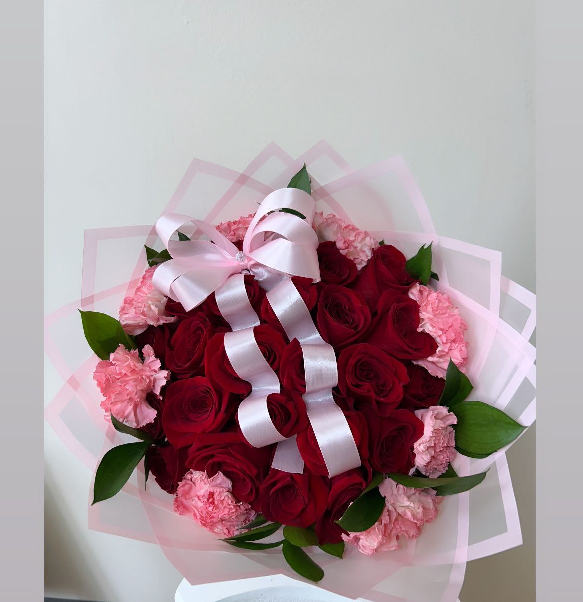 Bouquet of red roses and pink carnations with a pale pink ribbon