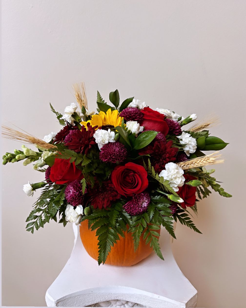 Mixed bouquet in a pumpkin vase with red roses and white blooms