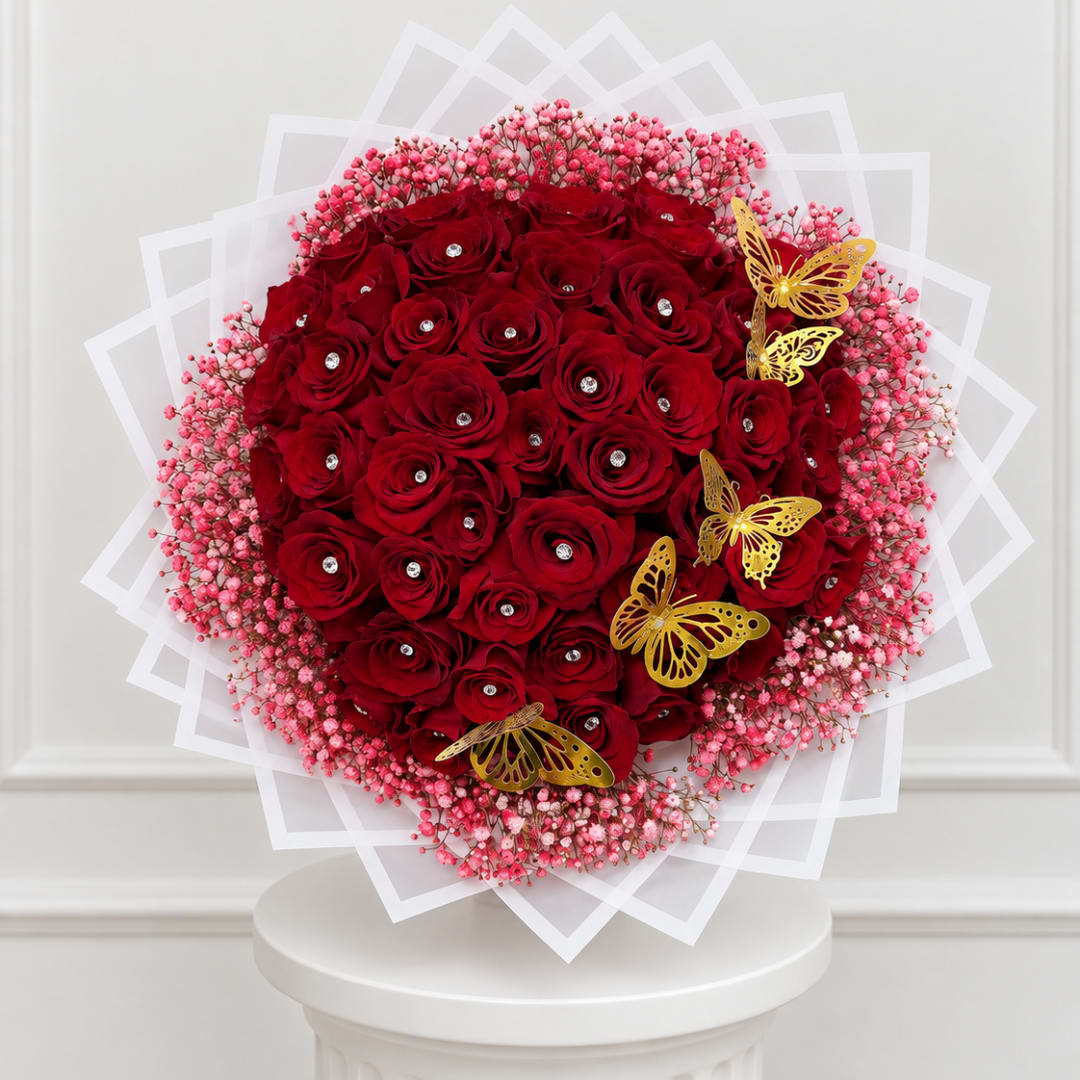 Round bouquet of red roses with pink filler and gold butterfly accents