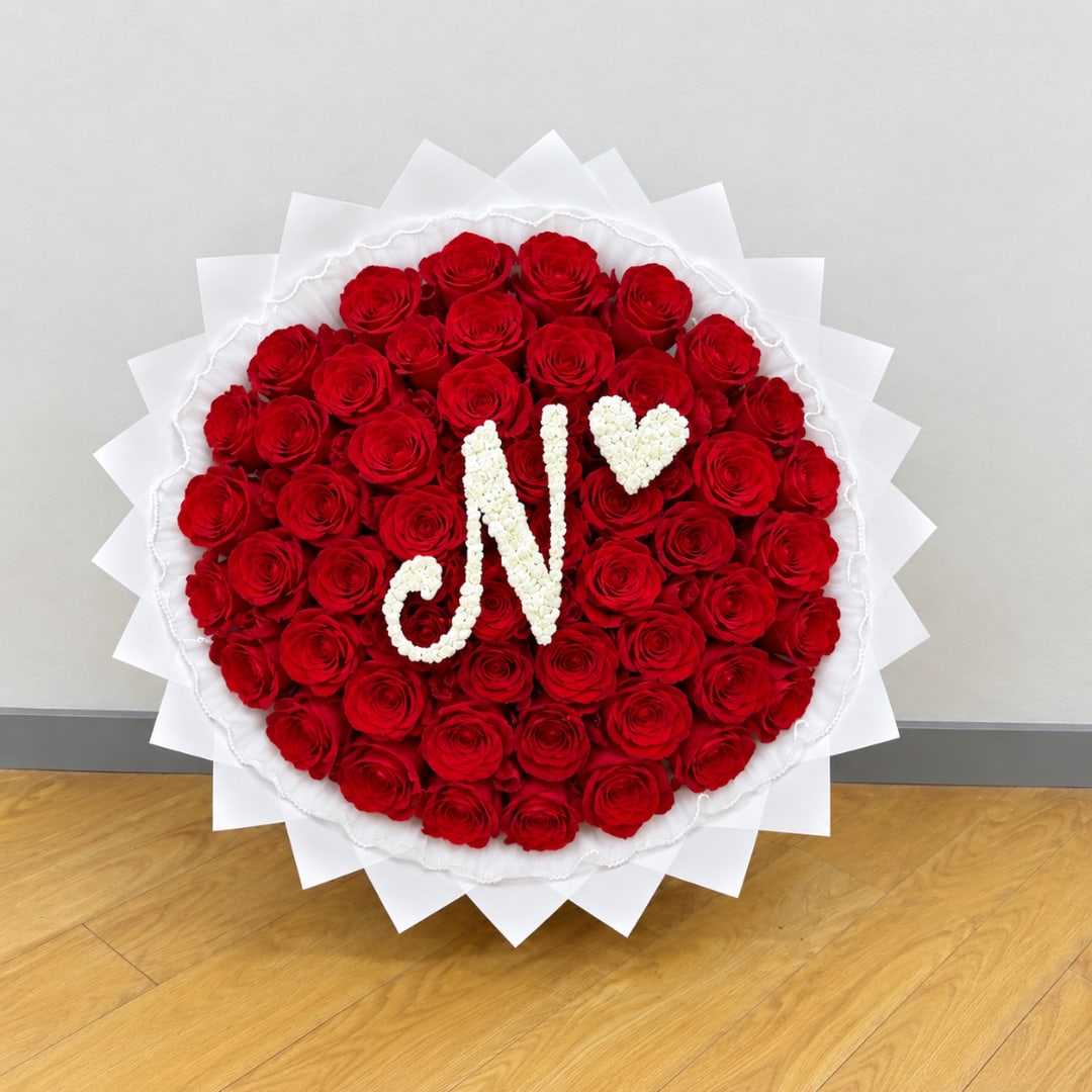 Heart-shaped red rose arrangement with white floral initials and a heart
