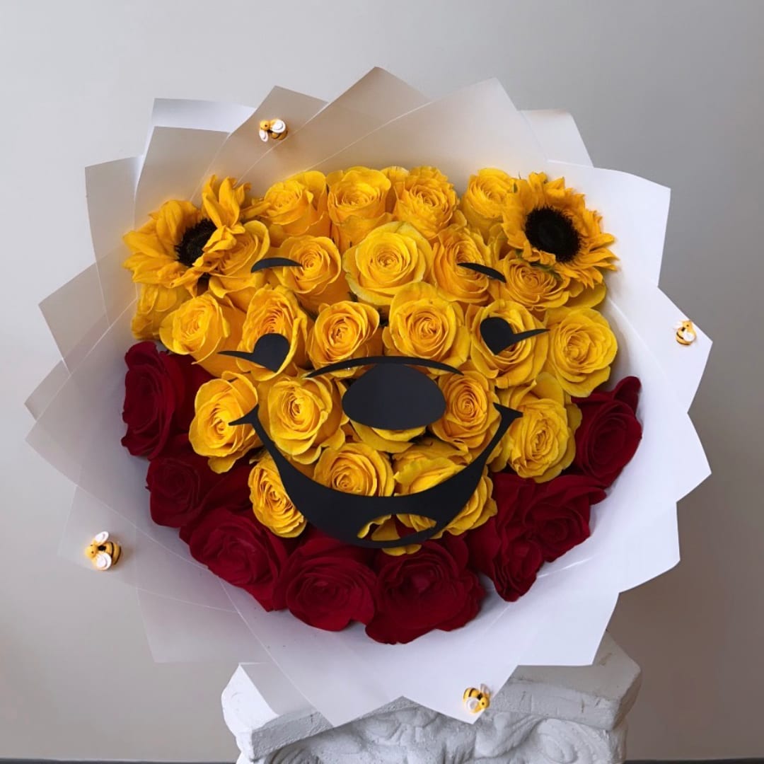 Yellow and red rose bouquet with sunflower accents and a bear face wrap
