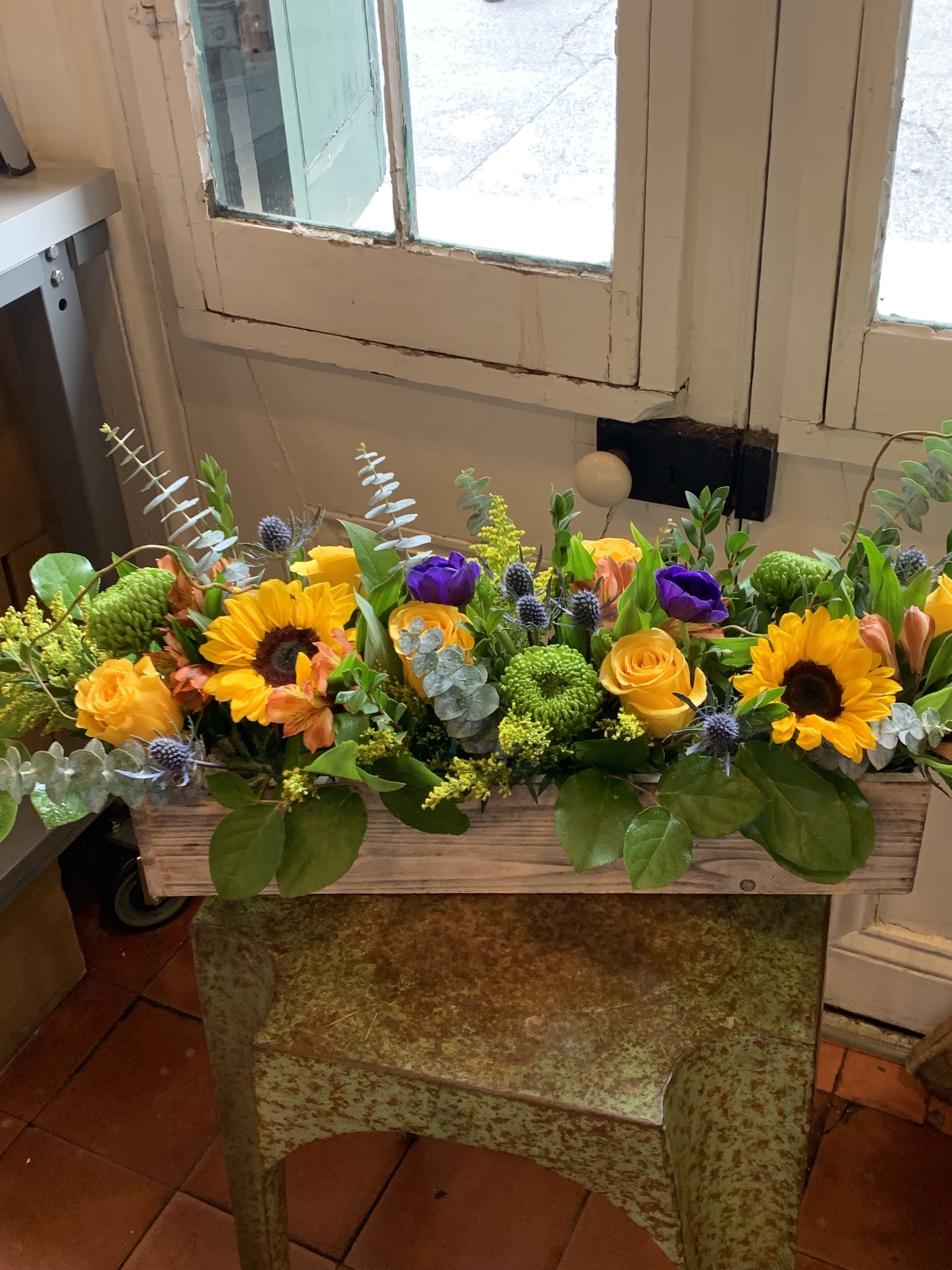 The Long and Low (spring edition) - Long centerpiece featuring happy sunflowers and "bumblebee roses". Everyone loves this one!