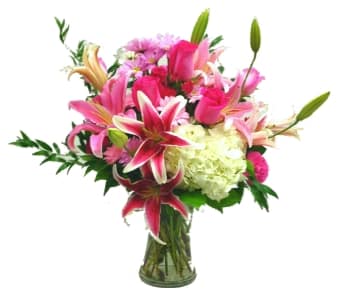 Pink lilies and roses in a glass vase with white hydrangea