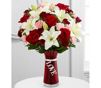 Bouquet of red roses, white lilies, and pink carnations in a red vase