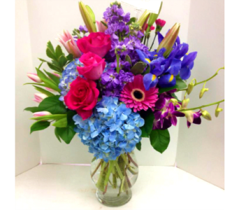 Colorful bouquet of roses, hydrangeas, irises, and orchids in a glass vase