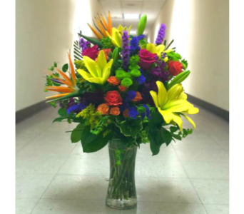 Tall mixed bouquet in a clear glass vase with bright lilies and roses