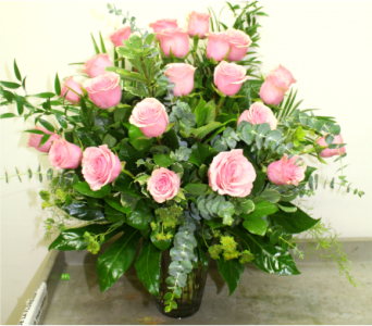Pink roses arranged in a clear glass vase with greenery