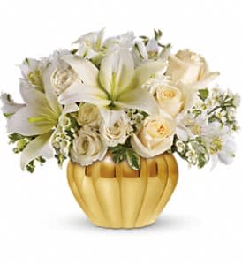 Short arrangement of white lilies and cream roses in a round gold vase