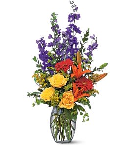 Mixed bouquet of purple, yellow, and orange flowers in a glass vase