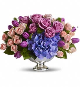 Purple and pink flower arrangement in a silver pedestal bowl