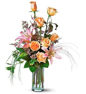 Orange roses and pink lilies in a clear glass vase