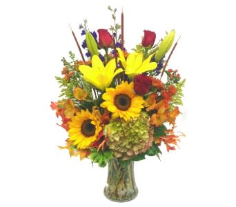 Bouquet of sunflowers, lilies, and red roses in a glass vase