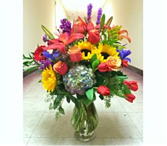 Colorful mixed bouquet in a clear glass vase with sunflowers and roses