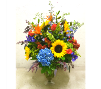 Colorful mixed bouquet in a clear glass vase with sunflowers and lilies