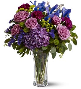 Purple and blue floral bouquet in a clear glass vase