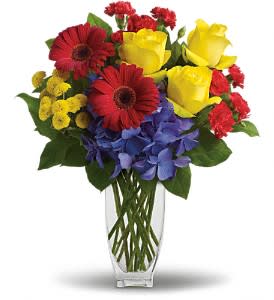 Bouquet of red, yellow, and blue flowers in a clear glass vase