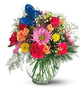 Colorful mixed bouquet in a clear glass vase with a blue butterfly decoration