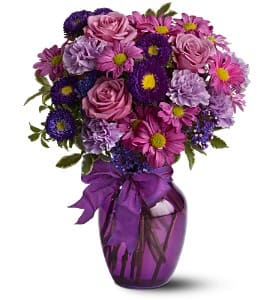 Purple and pink bouquet in a purple vase with a ribbon