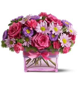 Pink roses and purple daisies in a pink glass vase with a ribbon