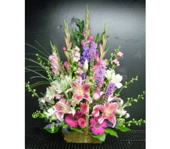 Tall pink and purple mixed flower arrangement in a wicker basket