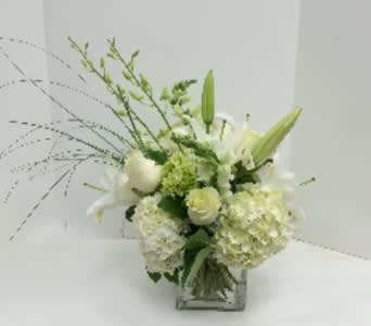 White floral arrangement with lilies and hydrangeas in a square glass vase