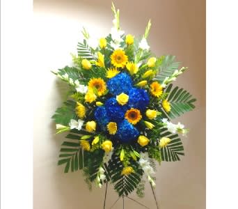 Tall standing spray with blue hydrangeas and yellow blooms on a metal easel