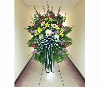 Tall mixed standing spray with lilies, roses, daisies, and ribbon on a metal easel