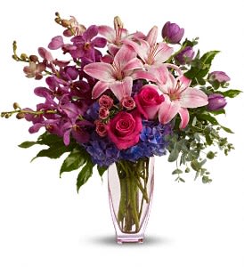 Pink lilies, roses, and purple orchids in a clear vase