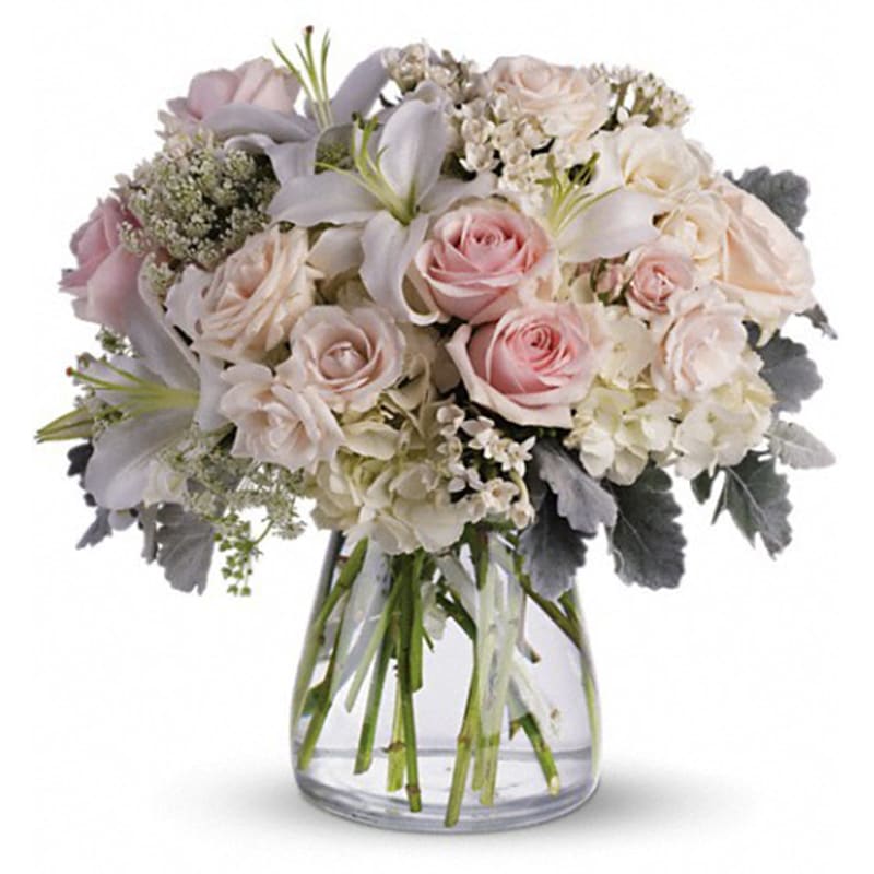Pink and white roses with lilies in a clear glass vase