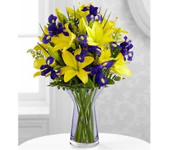 Yellow lilies and purple irises in a clear vase