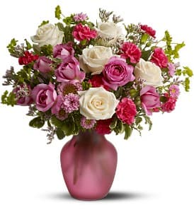 Pink and white roses arranged in a pink vase